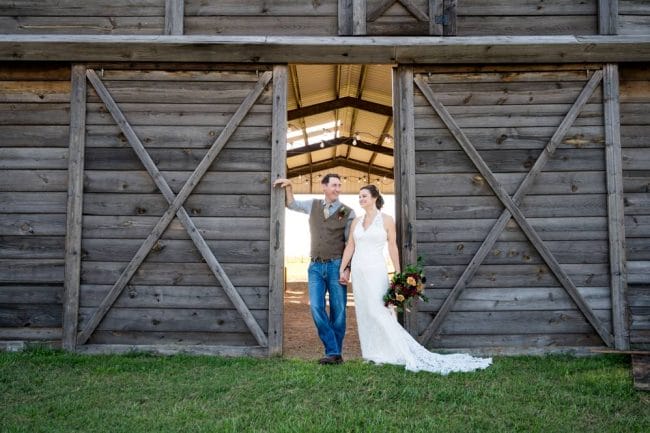 bride and groom in front of open barn doors